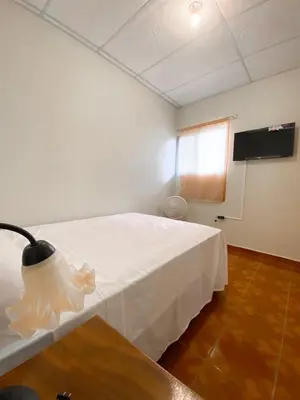 a room with a white bed and a flat screen tv at MARIA III HOSTAL in Juayúa