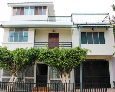 a white house with trees in front of it at MARIA III HOSTAL in Juayúa