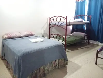 a bedroom with a bed with a blue blanket and bunk beds at Volcano Hostal y Restaurante in San Salvador