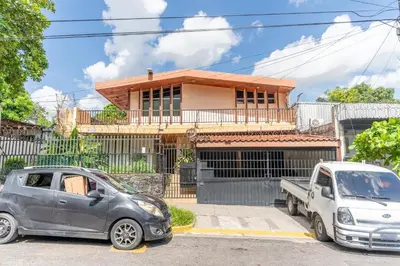 two cars parked in front of a house at Volcano Hostal y Restaurante in San Salvador