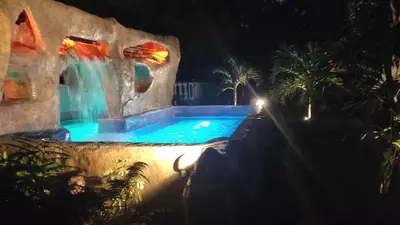 a pool with a waterfall and a water park at night at El Castillo de Piedra in San Miguel