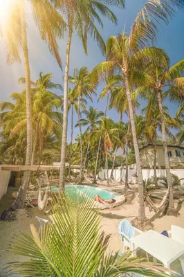 a pool on the beach with palm trees at Sunset Surf Villa in La Libertad