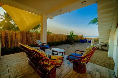 a patio with chairs and a table and a fence at Ocean Paradise in Barra de Santiago