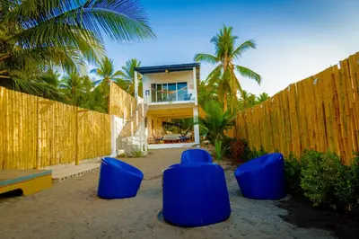 a house with blue chairs in front of a fence at Ocean Paradise in Barra de Santiago