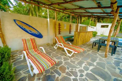 two chairs and a surfboard on a patio at Ocean Paradise in Barra de Santiago