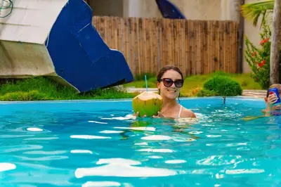 a woman holding a coconut in a swimming pool at Ocean Paradise in Barra de Santiago