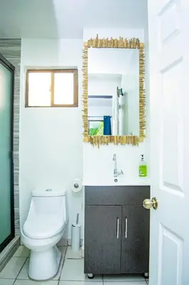 a bathroom with a toilet and a mirror at Buena Vista El Zonte in El Zonte
