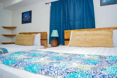 a bedroom with two beds and a blue curtain at Buena Vista El Zonte in El Zonte