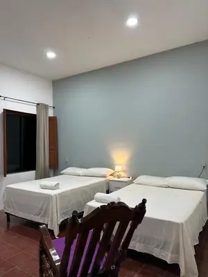 two beds in a room with two chairs at Hostal El Amate #2 in Suchitoto