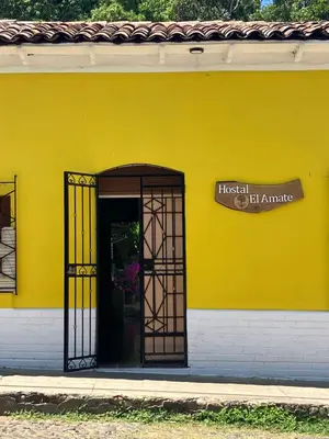 a yellow building with a door and a sign on it at Hostal El Amate #2 in Suchitoto