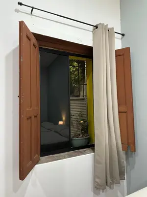 a window with a curtain and a bed in a room at Hostal El Amate #2 in Suchitoto