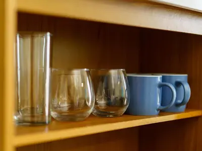 three empty glasses and a blue mug on a shelf at Acogedor Loft, Playa Las Flores in La Libertad