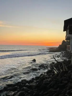 a beach with a house and the ocean at sunset at Acogedor Loft, Playa Las Flores in La Libertad