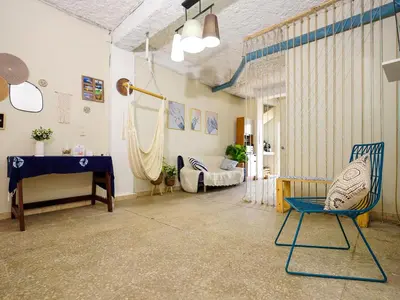 a living room with a blue chair and a piano at Acogedor Loft, Playa Las Flores in La Libertad