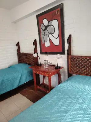 a room with two beds and a table and a picture at Chilamar Surf Lodge in La Libertad