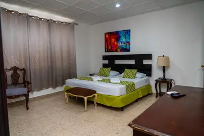 a bedroom with a bed and a table and a chair at Suites & Apartments San Benito - Zona Rosa in San Salvador
