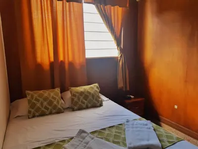 a small bedroom with a bed and a window at Suites & Apartments San Benito - Zona Rosa in San Salvador