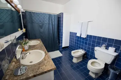 a blue tiled bathroom with two sinks and a toilet at Suites & Apartments San Benito - Zona Rosa in San Salvador