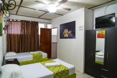 a room with two beds and a flat screen tv at Suites & Apartments San Benito - Zona Rosa in San Salvador