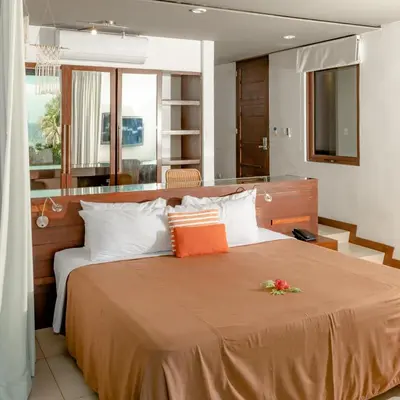 a bedroom with a large bed with orange and white pillows at Las Flores Resort in Chirilagua