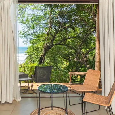 a patio with chairs and a table and a view of the ocean at Las Flores Resort in Chirilagua