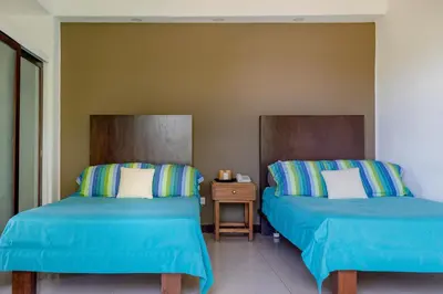 a room with two beds and a night stand at Las Flores Resort in Chirilagua
