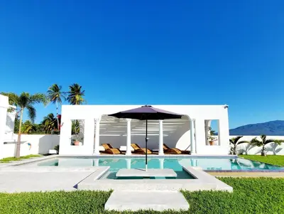 a swimming pool with an umbrella next to a house at CASA ROMA Hotel Boutique in El Tamarindo