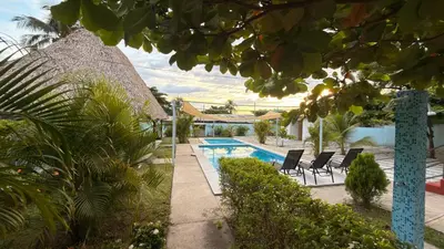 a villa with a swimming pool and chairs and trees at Lomeli’s Home, 5 minutos del Tunco in La Libertad
