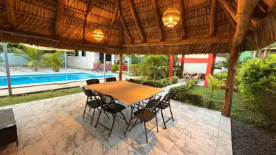 a wooden table and chairs under a wooden umbrella at Lomeli’s Home, 5 minutos del Tunco in La Libertad