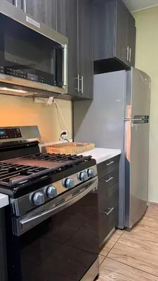 a kitchen with a stove and a stainless steel refrigerator at Lomeli’s Home, 5 minutos del Tunco in La Libertad
