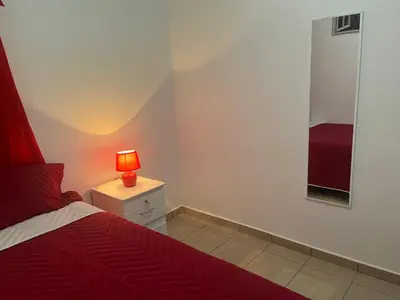 a bedroom with a red bed and a lamp on a night stand at Dream of angels home in Santa Ana