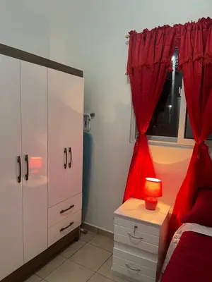 a bedroom with red curtains and a bed with a lamp at Dream of angels home in Santa Ana