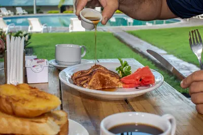 a person pouring syrup onto a plate of food at Atami Escape Resort in La Libertad