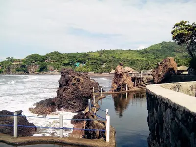 a body of water with rocks and a fence at Atami Escape Resort in La Libertad