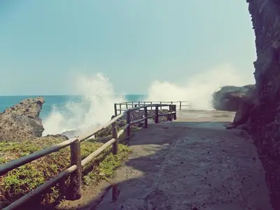 a wave crashing on a beach with a wooden fence at Atami Escape Resort in La Libertad
