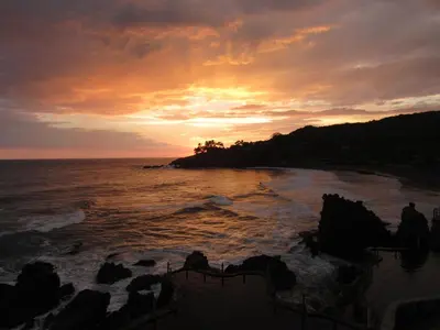 a sunset over the ocean with people on the beach at Atami Escape Resort in La Libertad