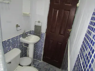 a bathroom with a toilet and a sink and a door at Casa Vieja Guest House in Santa Ana