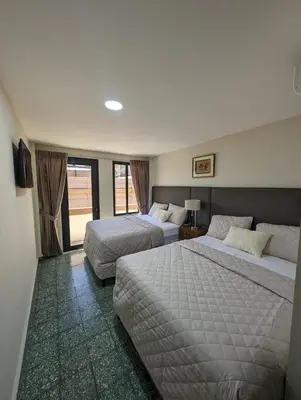 a hotel room with two beds and a window at Hotel Abrego in San Salvador