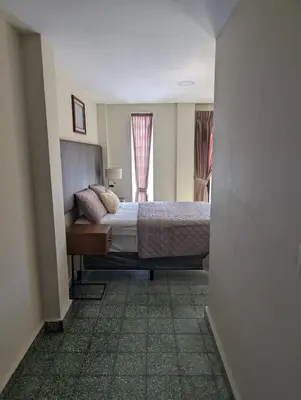 a bedroom with a bed and a window at Hotel Abrego in San Salvador