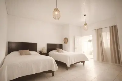 two beds in a bedroom with white walls at Habitación Deluxe Tierra - Villa Valle Campo in Nahuizalco