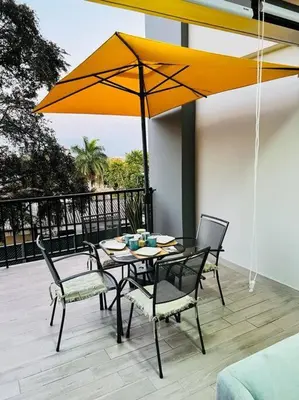 a table and chairs with an umbrella on a patio at Elegante y acogedor apartamento en el corazón de San Salvador in San Salvador