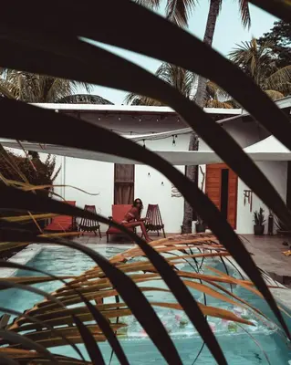a woman sitting in a chair next to a swimming pool at 3 Family Villa Private Pool Parking BBQ El Sunzal El Tunco El Zonte SURFCITY in Tamanique