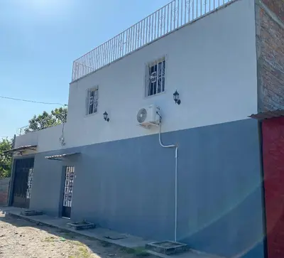 a white building with two windows on the side of it at Habitación cerca del aeropuerto #1 in Tilapa