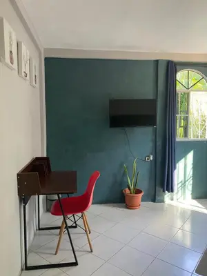 a living room with a red chair and a piano at Habitación cerca del aeropuerto #1 in Tilapa