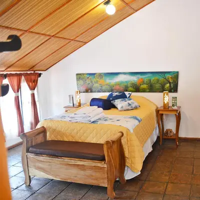 a bedroom with a bed with a painting on the wall at Hostal Santa Clara B&B in Apaneca
