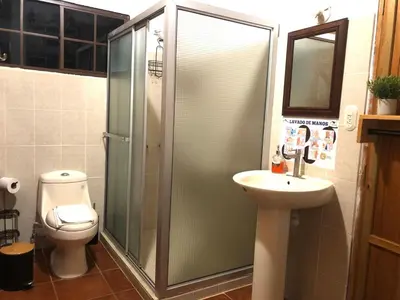 a bathroom with a shower and a sink and a toilet at Hostal Santa Clara B&B in Apaneca