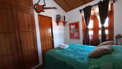 a bedroom with a bed with blue sheets and a window at Hostal Santa Clara B&B in Apaneca
