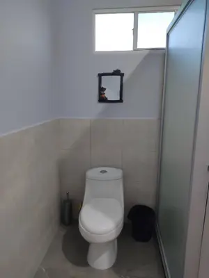 a white toilet in a bathroom with a window at Rancho Del Oso Tuerto in Marcelino