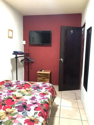 a bedroom with a bed and a flat screen tv on a red wall at Comfort Home Escalón in San Salvador