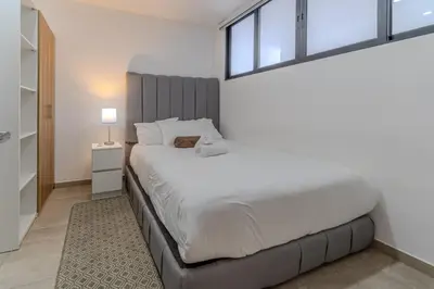 a bedroom with a large white bed and a window at Margo 306- Luxe, Elegant & Cozy Condo- City Center in San Salvador